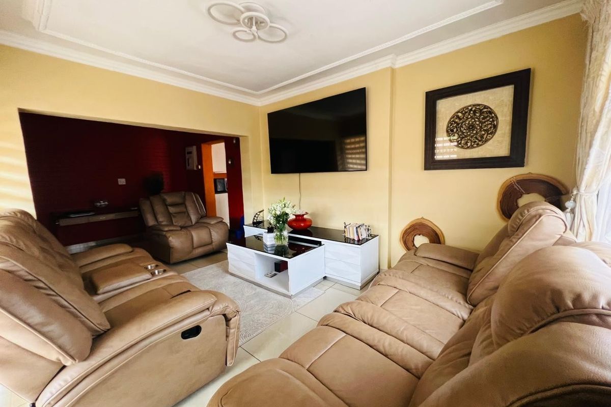 A comfortable living room featuring tiled flooring, decorative ceiling cornicing, and a recessed wall area, providing a functional space for relaxation.
