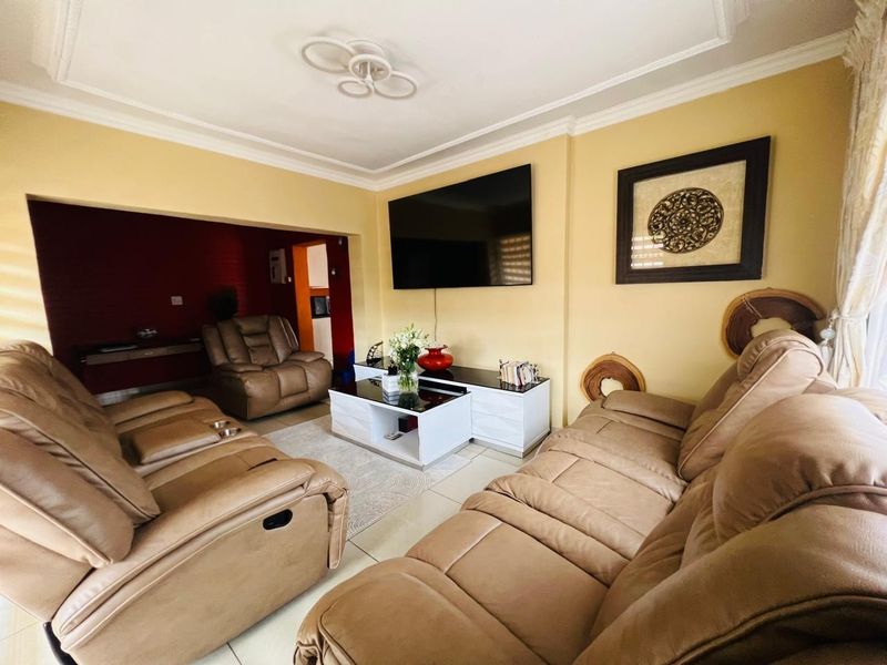 A comfortable living room featuring tiled flooring, decorative ceiling cornicing, and a recessed wall area, providing a functional space for relaxation.