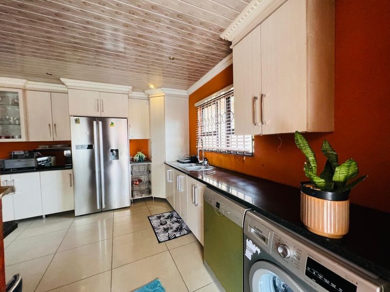 A functional kitchen featuring built-in cabinetry, tiled flooring, and integrated appliances, offering a practical layout with potential for cosmetic updates.