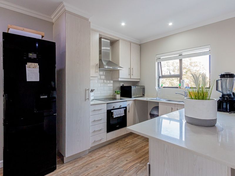 Modern kitchen featuring light wood cabinetry, stone countertops, subway tile backsplash, integrated stainless steel appliances, and durable laminate flooring.