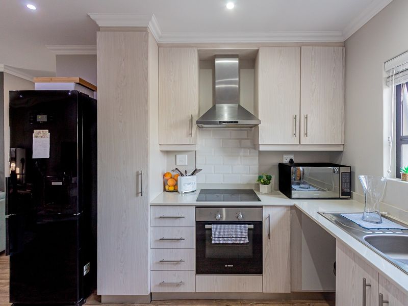 Modern kitchen featuring light wood-grain cabinetry, subway tile backsplash, integrated stainless steel appliances, and a functional layout with ample counter space.