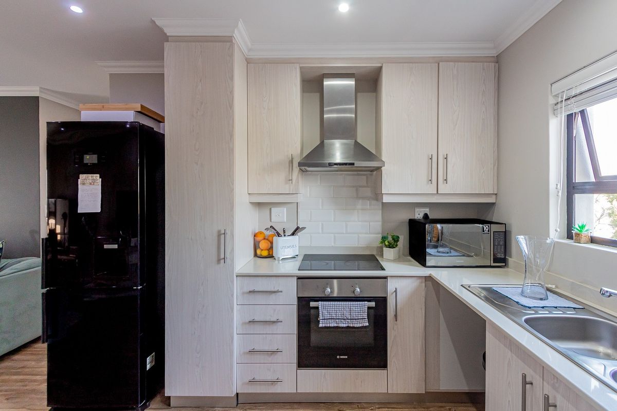 Modern kitchen featuring light wood-grain cabinetry, subway tile backsplash, integrated stainless steel appliances, and a functional layout with ample counter space.