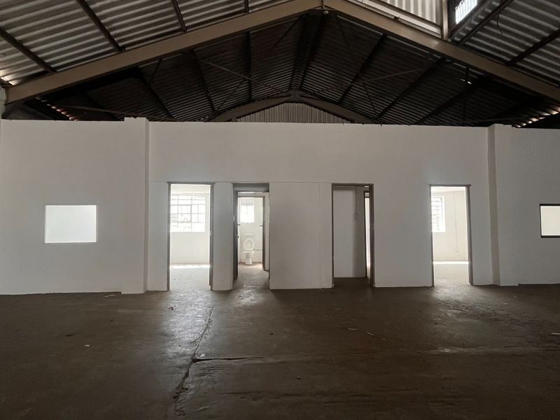 Spacious industrial utility area featuring exposed steel roof trusses, concrete flooring, and multiple internal access points with a visible fire safety installation.
