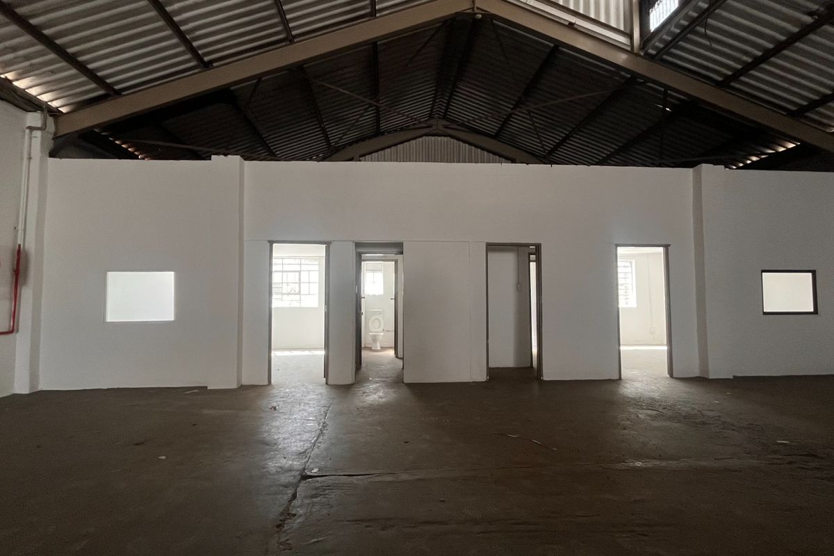 Spacious industrial utility area featuring exposed steel roof trusses, concrete flooring, and multiple internal access points with a visible fire safety installation.
