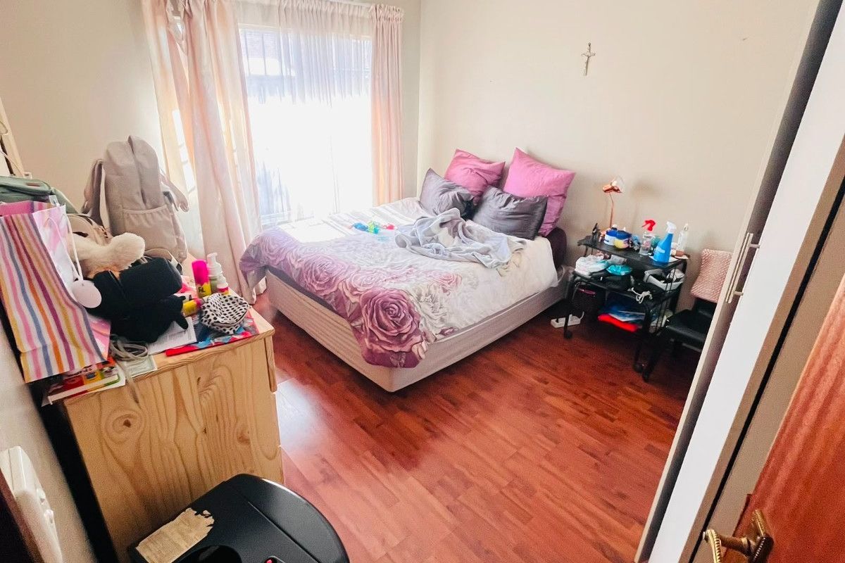 A standard bedroom featuring laminate flooring and a window with curtain tracks, providing a functional living space.
