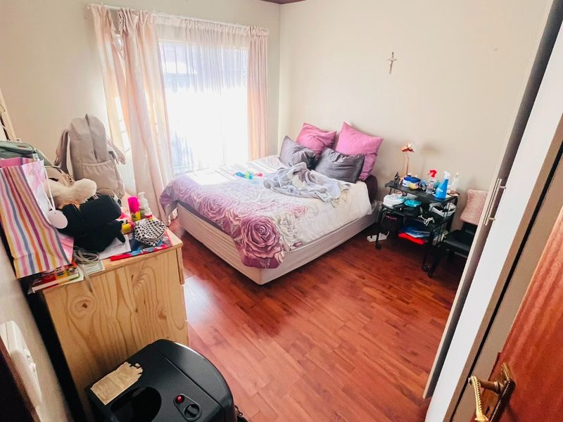 A standard bedroom featuring laminate flooring and a window with curtain tracks, providing a functional living space.