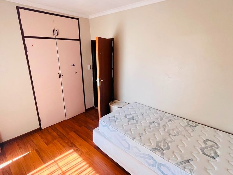 A bedroom featuring laminate flooring, built-in cupboards, and a coved ceiling, offering a functional space ready for cosmetic updates.
