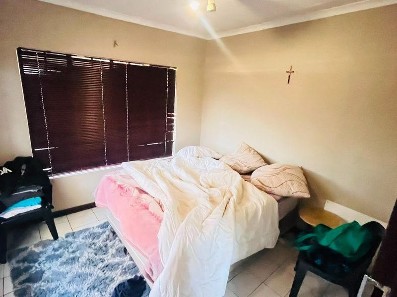 A bedroom featuring tiled flooring, venetian blinds, and a ceiling-mounted spotlight fixture.