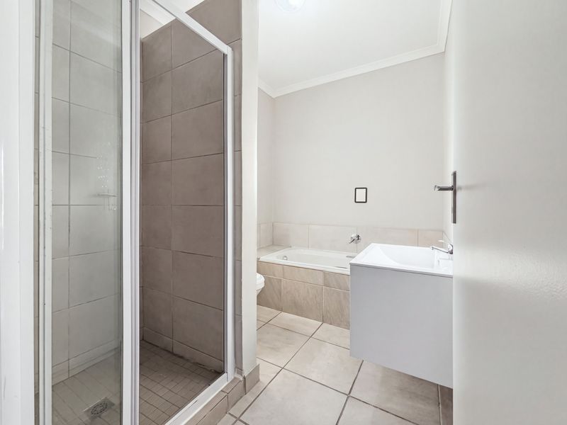 A clean, modern bathroom featuring a separate shower enclosure, a built-in bathtub, and a wall-mounted vanity with neutral tiling throughout.