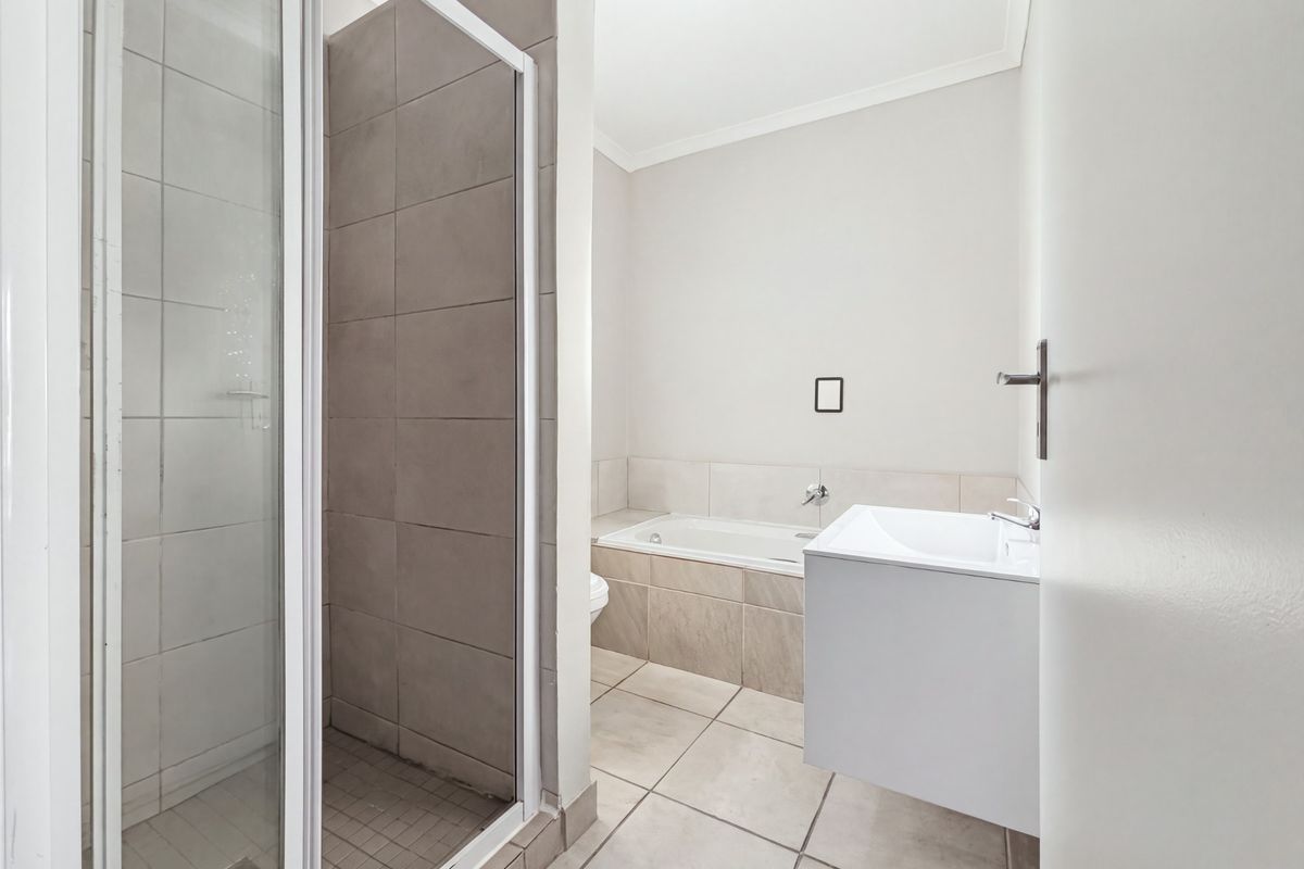 A clean, modern bathroom featuring a separate shower enclosure, a built-in bathtub, and a wall-mounted vanity with neutral tiling throughout.