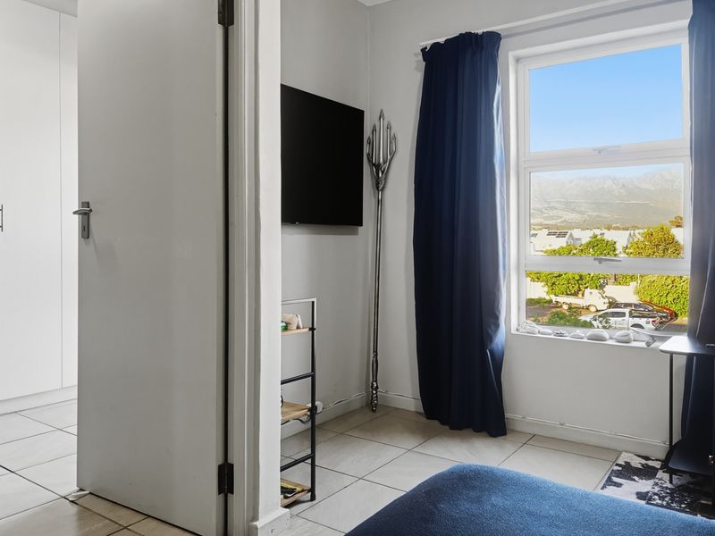 A bedroom featuring tiled flooring, a built-in cupboard, and a window with views of the surrounding area.