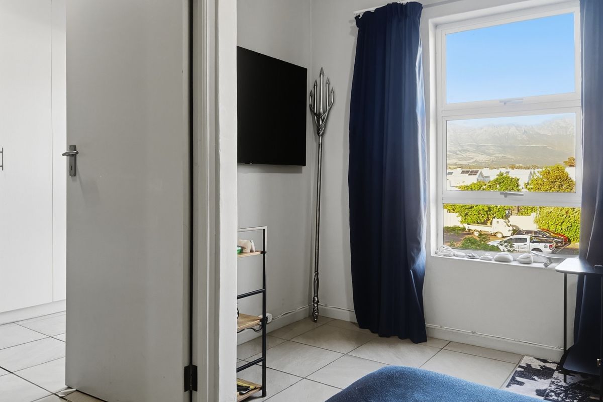 A bedroom featuring tiled flooring, a built-in cupboard, and a window with views of the surrounding area.