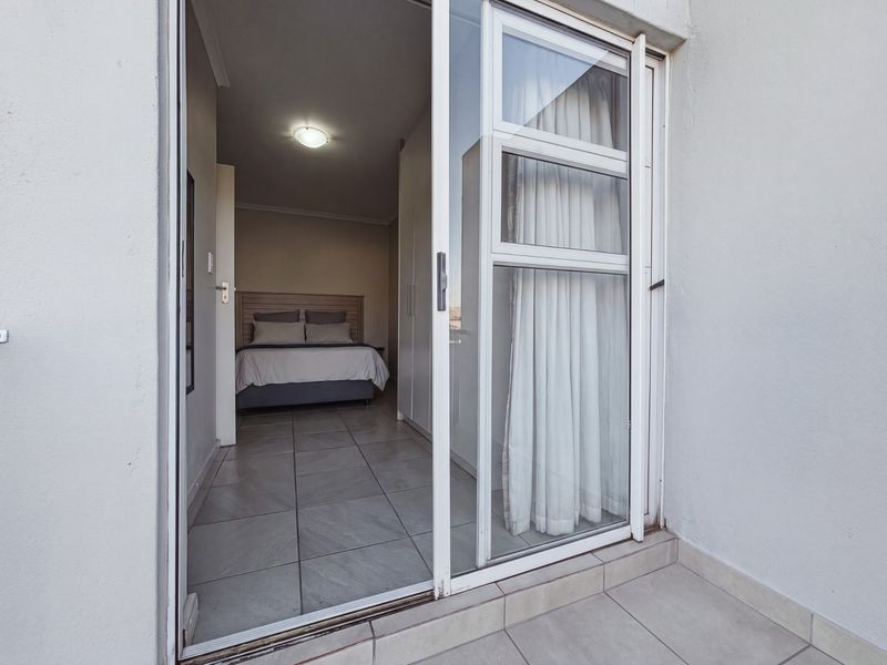 A bedroom featuring tiled flooring, built-in cupboards, and a sliding glass door providing access to an outdoor area.
