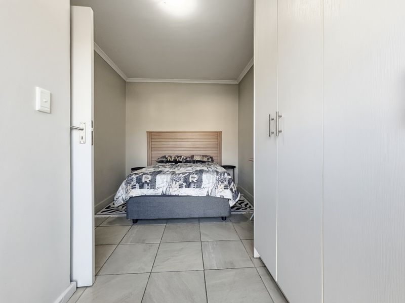 A well-maintained bedroom featuring neutral wall tones, tiled flooring, and ample built-in cupboard storage.
