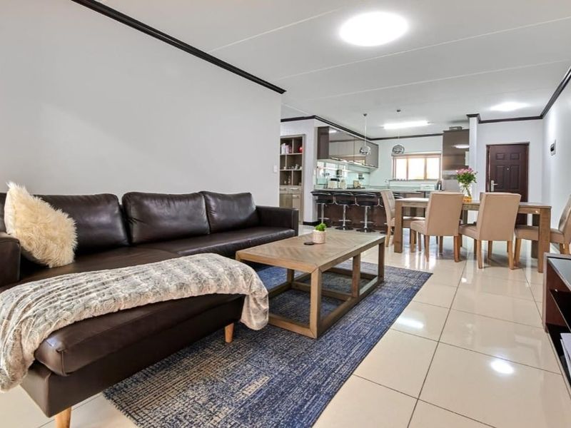 Spacious open-plan living and dining area featuring modern tiled floors, recessed lighting, and a well-appointed kitchen with a breakfast island.