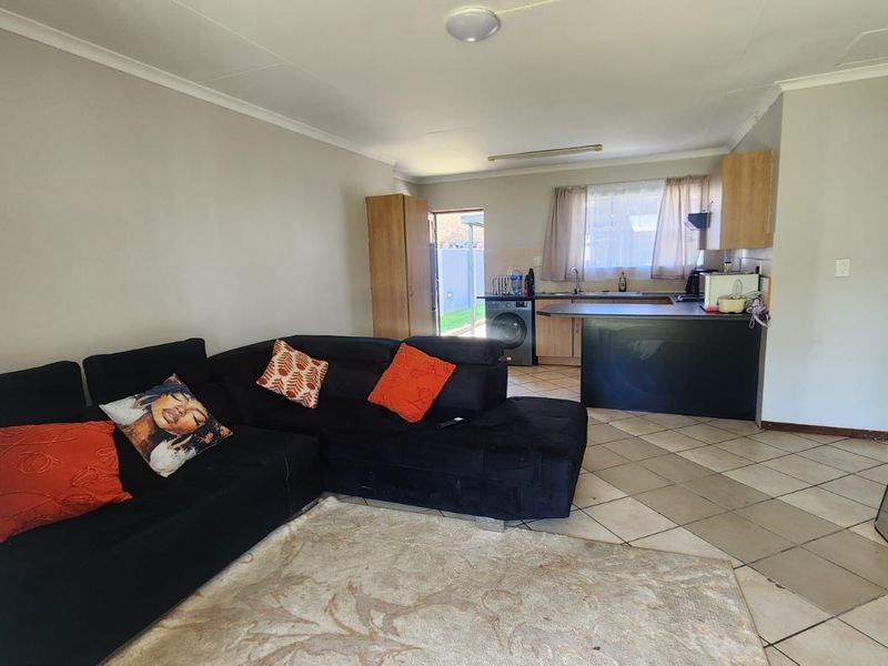 Open-plan living area featuring tiled flooring and a functional kitchen space with built-in cabinetry and countertops.