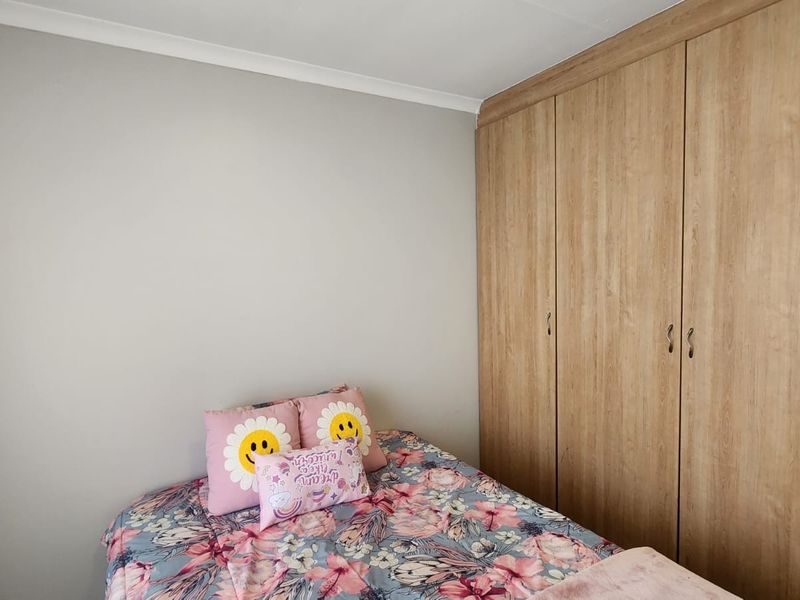 A well-maintained bedroom featuring light-toned built-in cupboards and neutral wall finishes.