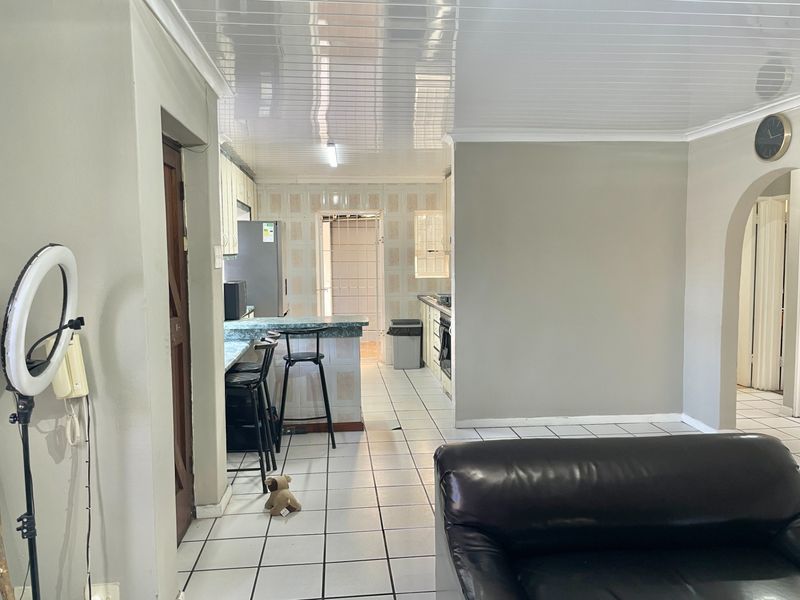 Open plan living and kitchen area featuring tiled flooring, a breakfast bar, and built-in cabinetry with integrated stove and oven.