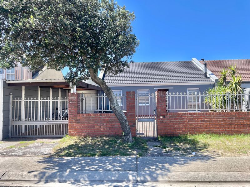 Front elevation of a residential house featuring a brick boundary wall, metal security fencing, a carport, and a tiled roof.