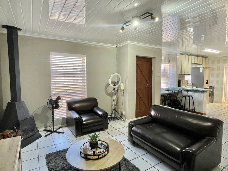 Open plan living area featuring a freestanding fireplace, tiled flooring, and an adjoining kitchen with breakfast counter and built-in cabinetry.