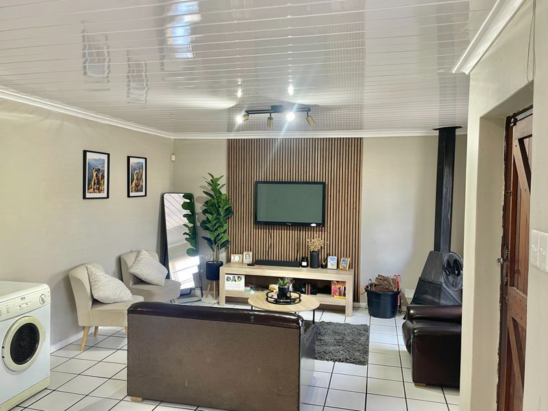 A comfortable living room featuring a modern wood-slat accent wall, a built-in fireplace, tiled flooring, and a clean PVC ceiling finish.