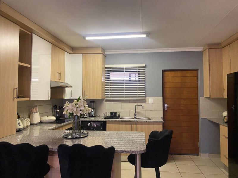A well-maintained kitchen featuring granite countertops, modern cabinetry, a tiled backsplash, and a functional layout with a breakfast bar area.