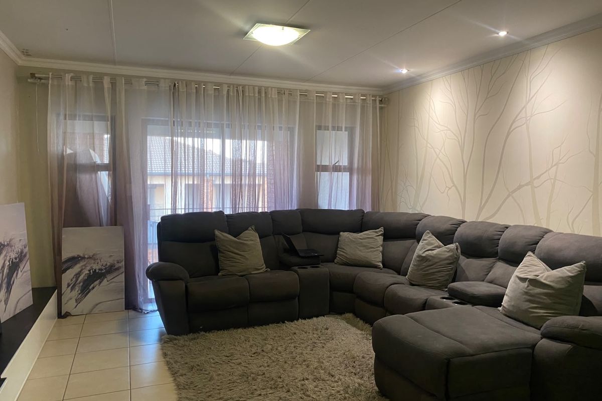 A comfortable living room featuring tiled flooring, recessed lighting, and a large sliding glass door providing access to the exterior.