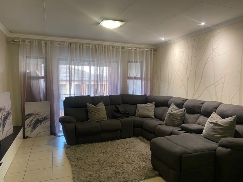 A comfortable living room featuring tiled flooring, recessed lighting, and a large sliding glass door providing access to the exterior.