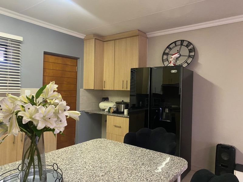 A functional kitchen area featuring light wood-toned built-in cabinetry, granite countertops, and a tiled backsplash, providing a clean and practical workspace.