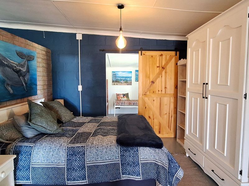A bedroom featuring an exposed brick feature wall, dark blue painted walls, and a rustic sliding barn door leading to an adjacent space.