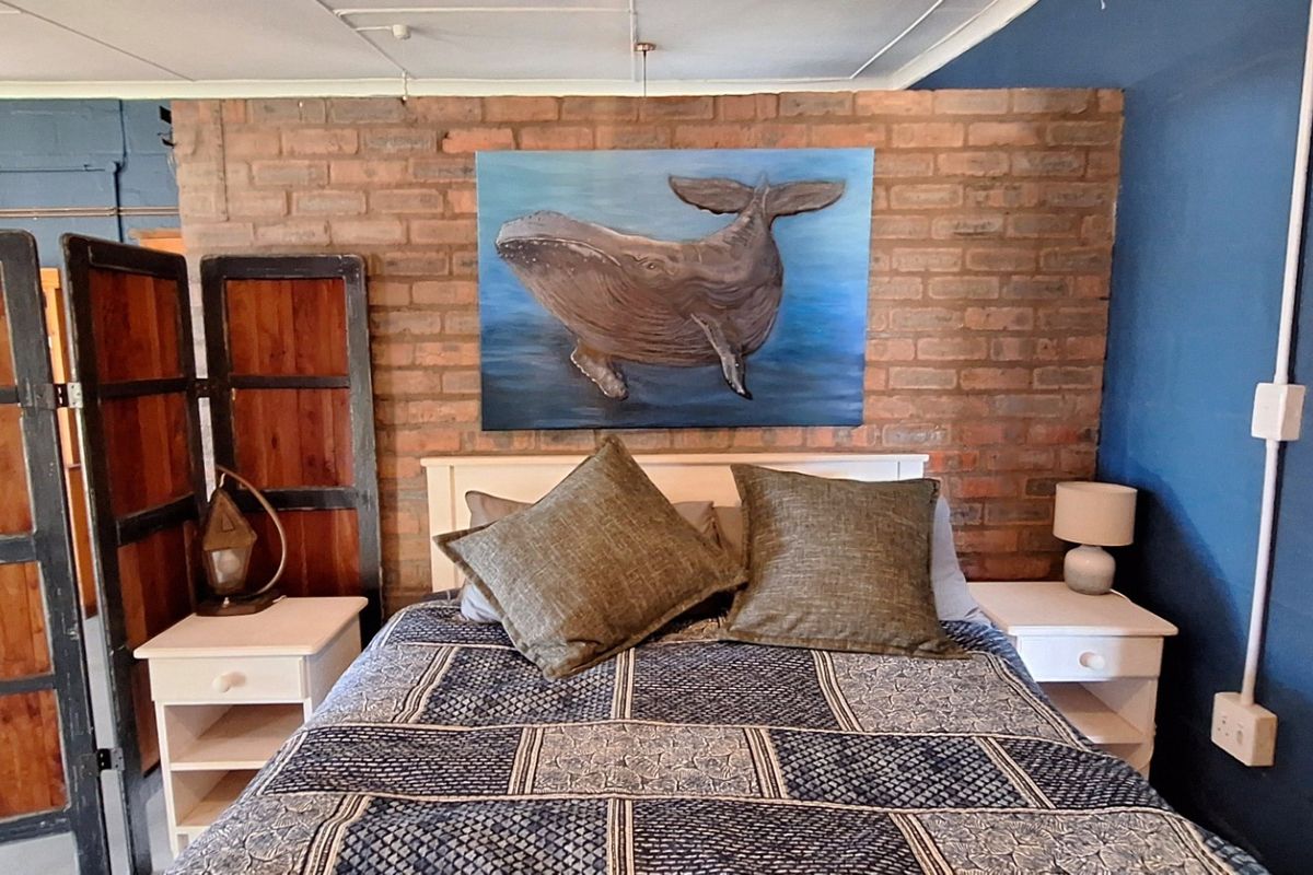 Bedroom featuring an exposed brick feature wall and surface-mounted electrical conduit, offering a rustic aesthetic with potential for modern refinement.