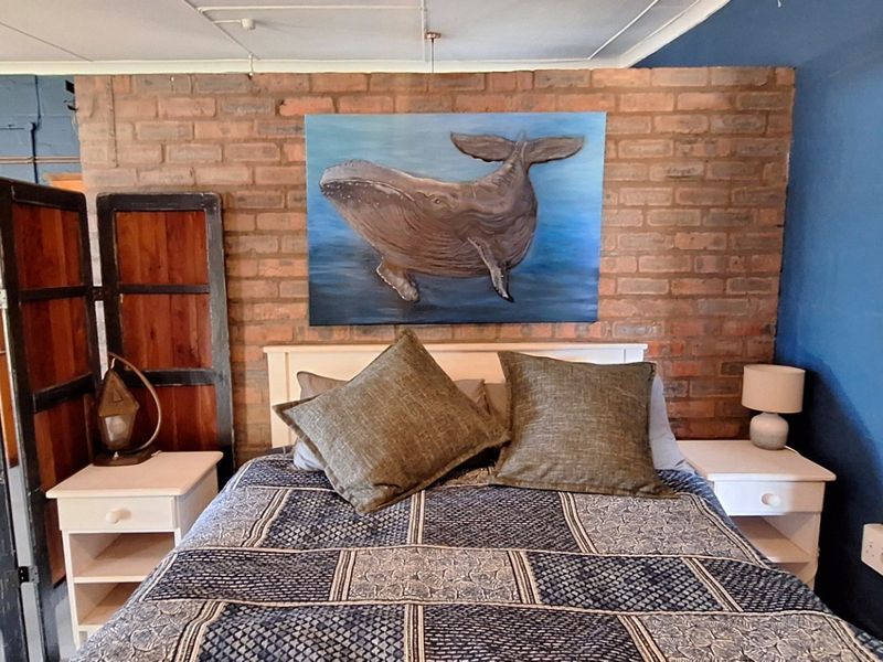Bedroom featuring an exposed brick feature wall and surface-mounted electrical conduit, offering a rustic aesthetic with potential for modern refinement.