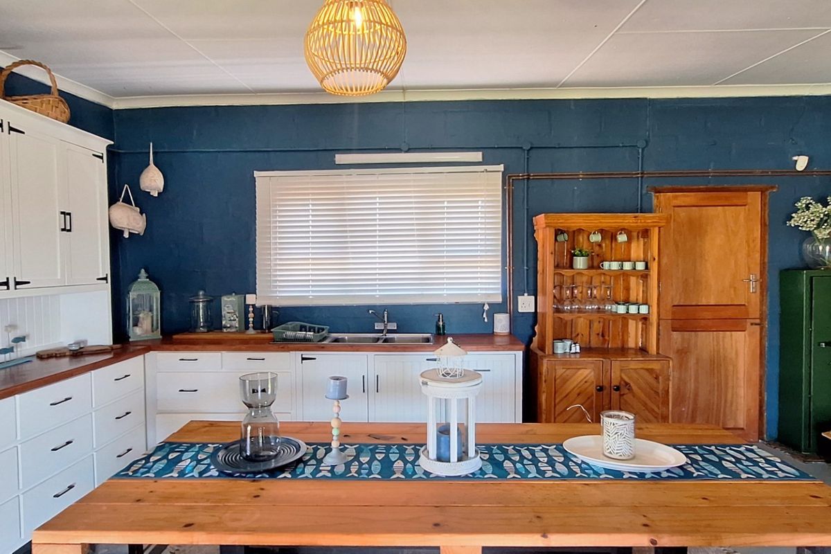 A charming kitchen featuring white built-in cabinetry, warm wooden countertops, a double basin sink, and a rustic sliding barn door.