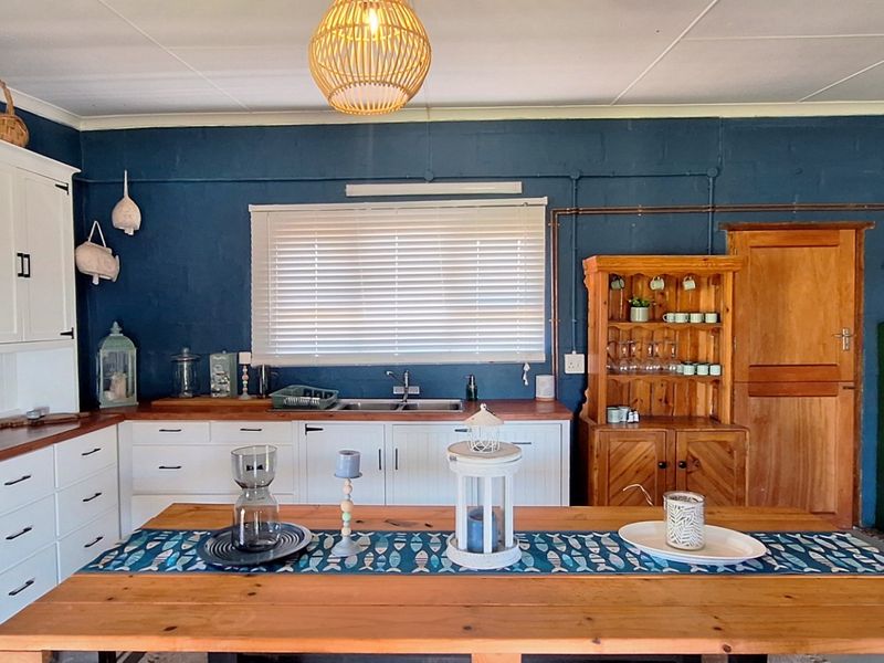 A charming kitchen featuring white built-in cabinetry, warm wooden countertops, a double basin sink, and a rustic sliding barn door.