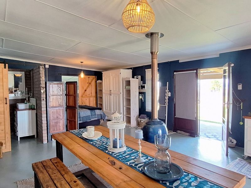 Spacious open-plan living area featuring a central freestanding fireplace, exposed brick accents, and direct access to the outdoor patio through a glass door.