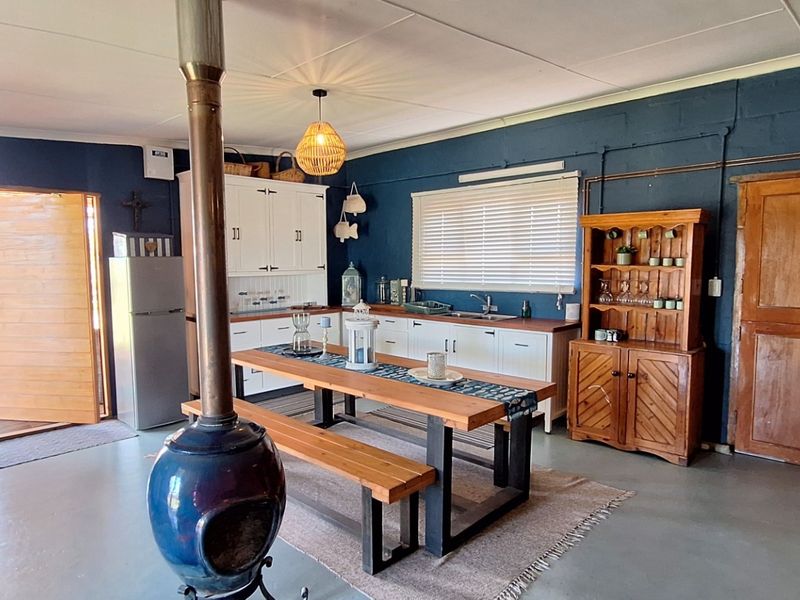 Open-plan living and kitchen area featuring a central fireplace, built-in cabinetry, and direct access to an outdoor patio space.