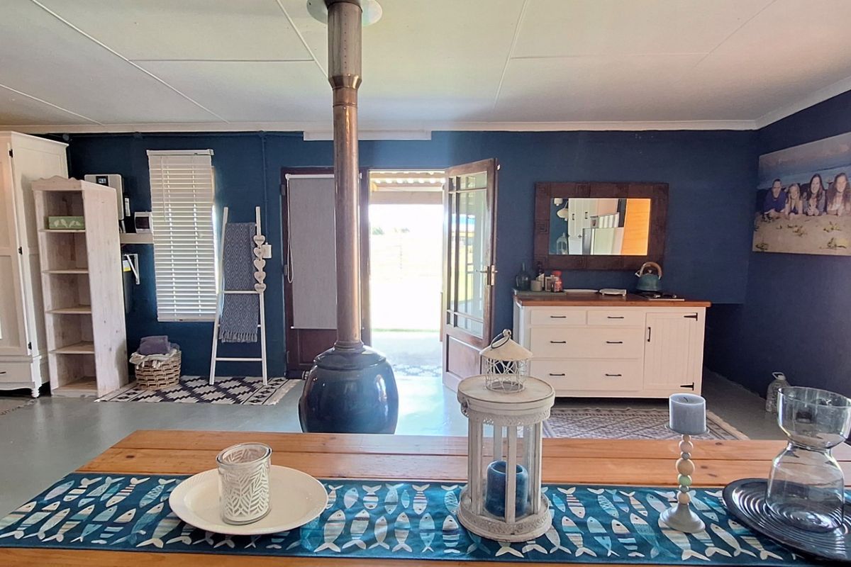 A living area featuring a central freestanding fireplace, painted concrete floors, and direct access to an outdoor patio through a timber door.