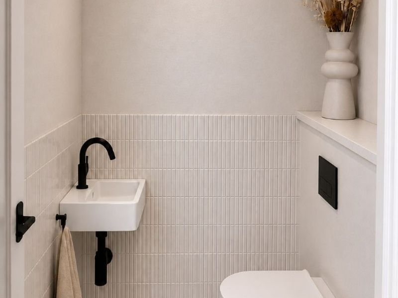 A modern, minimalist powder room featuring a wall-mounted toilet, concealed cistern, and a compact wall-mounted basin with matte black fixtures.