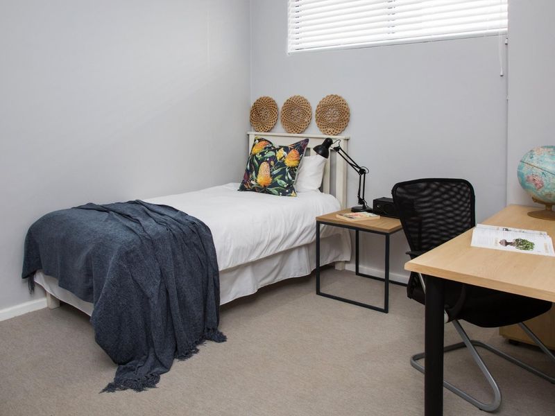 A well-maintained bedroom featuring neutral wall tones and venetian blinds, providing a clean and functional space.