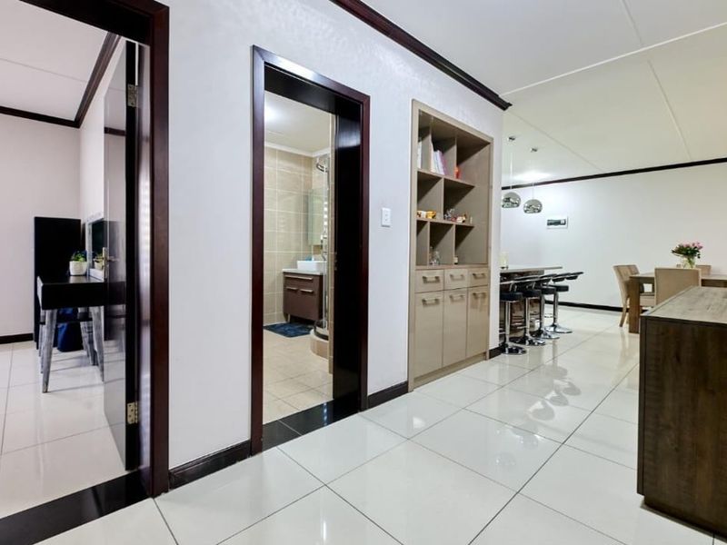 Open plan living area featuring polished tiled flooring, built-in storage cabinetry, and seamless transitions between the hallway, bathroom, and dining space.