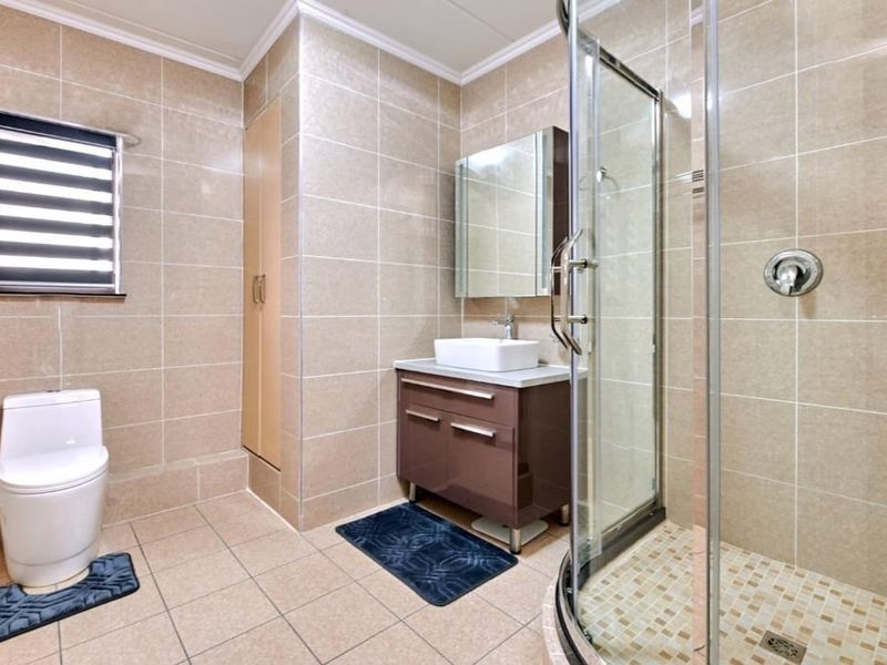 Modern bathroom featuring a glass shower enclosure, vessel sink vanity, medicine cabinet, and neutral floor-to-ceiling wall tiling.