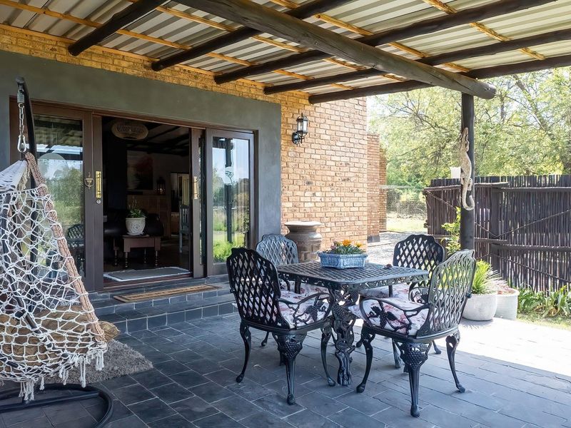A covered outdoor patio featuring slate flooring, exposed timber beams, and facebrick walls, providing a seamless transition to the interior living space.