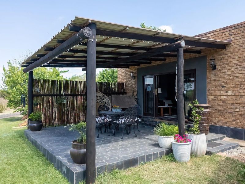 A covered outdoor patio featuring a timber pergola, tiled flooring, and a brick exterior, providing a functional space for outdoor relaxation.