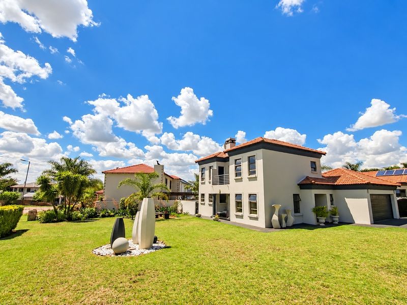 A well-maintained double-storey house featuring a terracotta tiled roof, a balcony, an attached garage, and a spacious landscaped rear garden.
