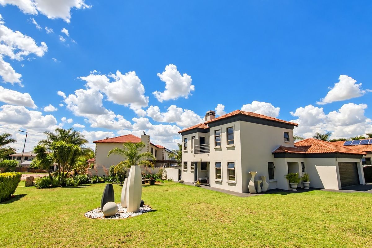 A well-maintained double-storey house featuring a terracotta tiled roof, a balcony, an attached garage, and a spacious landscaped rear garden.