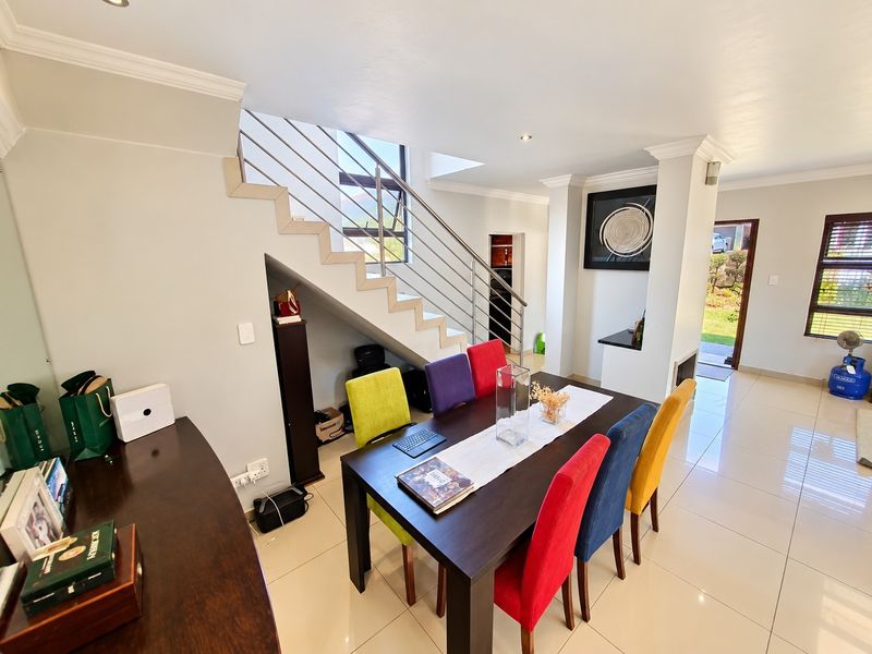 Open plan dining area featuring tiled flooring, recessed lighting, and a modern staircase with stainless steel balustrades leading to the upper level.