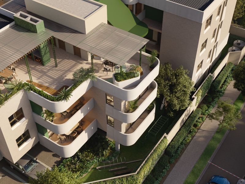 Aerial view of a modern apartment complex featuring tiered balconies, a rooftop terrace with pergola, solar panels, and landscaped ground-level gardens.