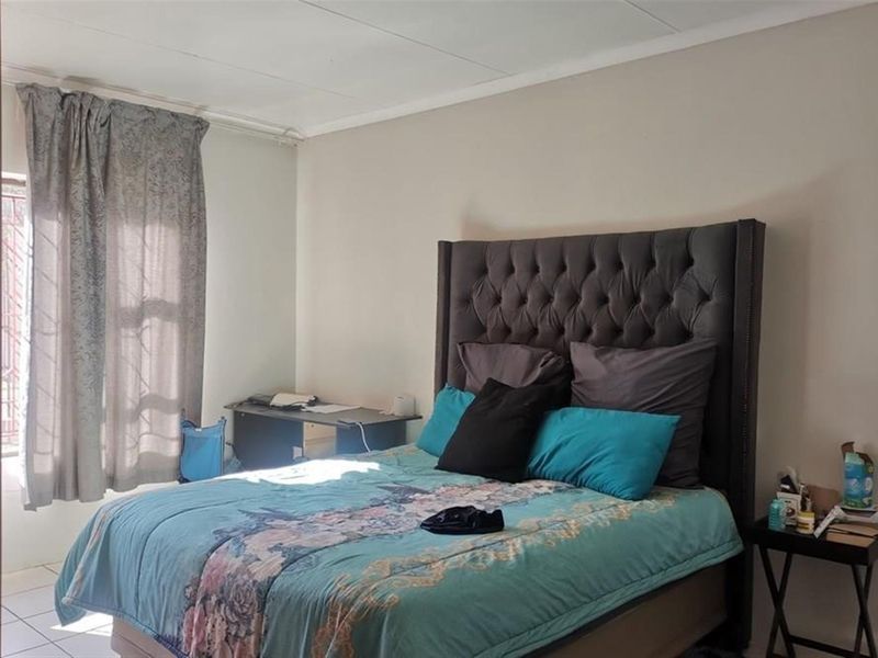 A functional bedroom featuring tiled flooring and neutral wall finishes, providing a comfortable space with natural light access.