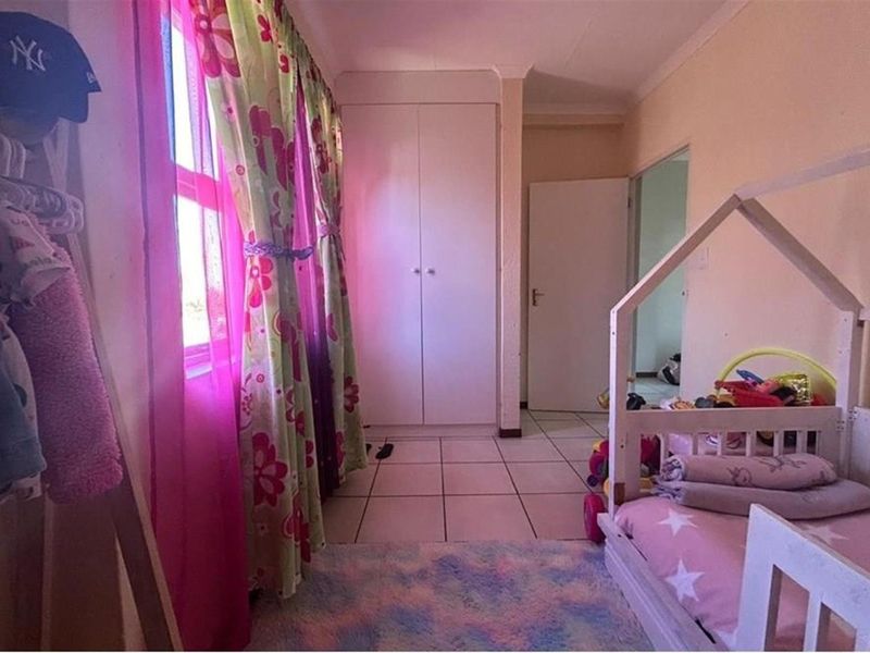A bedroom featuring tiled flooring and a built-in wardrobe, providing functional storage space within the townhouse.