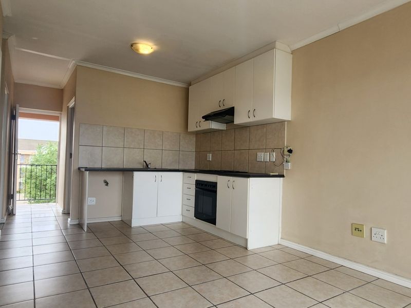 Open-plan kitchen area featuring tiled flooring, built-in cabinetry, integrated oven, and direct access to a balcony.